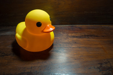 Yellow rubber duck on the table wood dark tone