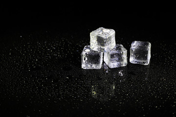 ice cubes reflection on black table background.