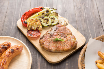 Fried pork chop and sausage on wooden background