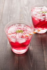 Red Cocktail with mint and ice on wooden table