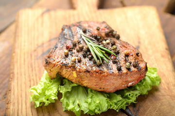 Grilled beef steak with rosemary, salt and pepper on cutting board