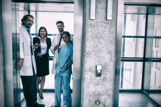 Doctors and businesswoman standing in elevator - Powered by Adobe