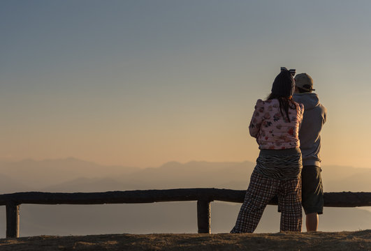 Man and Woman watching the sunrise on the mountain.