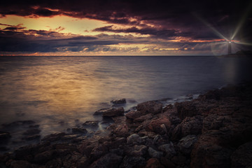 Lighthouse on the seashore at night with rays of light
