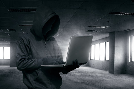 Hooded man with mask using laptop to hacking