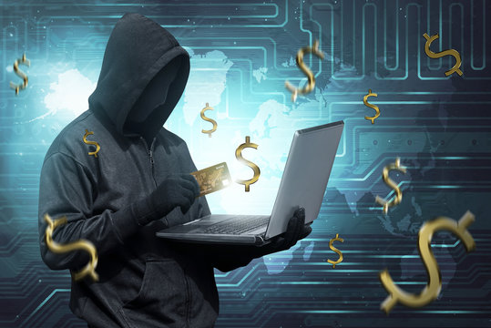 Hacker man with mask holding credit card with laptop on his hand
