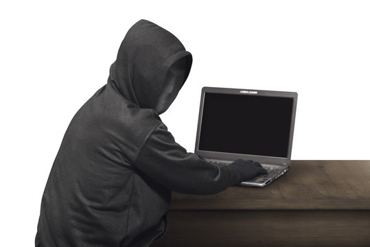 Portrait of hacker man with mask looking back while typing laptop on desk