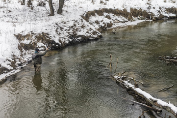 Fisherman with rod on a winter river. Tenkara fishing.