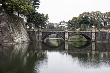 A beautiful bridge on a river can be seen in the picture. By looking at the style of the bridge we can say that it is an old bridge.