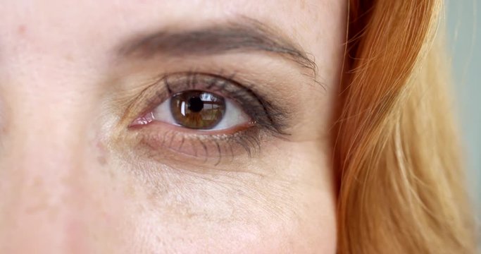 Extreme close-up of a brown eye of a woman with a foxy hair/Slow motion shot of the left eye of a woman with foxy hair