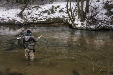 Fisherman with rod on a winter river. Tenkara fishing.
