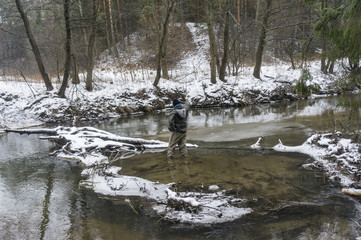 Fisherman with rod on a winter river. Tenkara fishing.