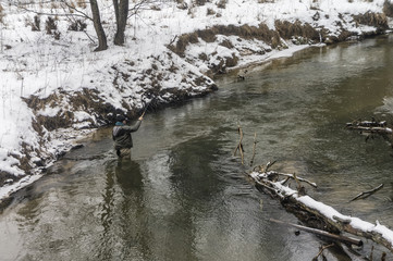 Fisherman with rod on a winter river. Tenkara fishing.