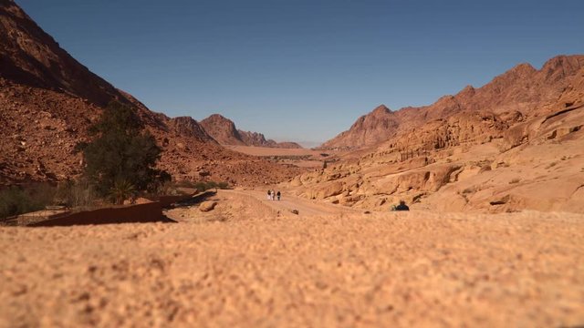 People walking along the road between the desert mountains. Individuals can not see