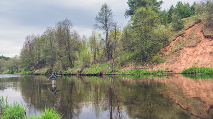 Fisherman fishing on a small spring river. Fly fishing.