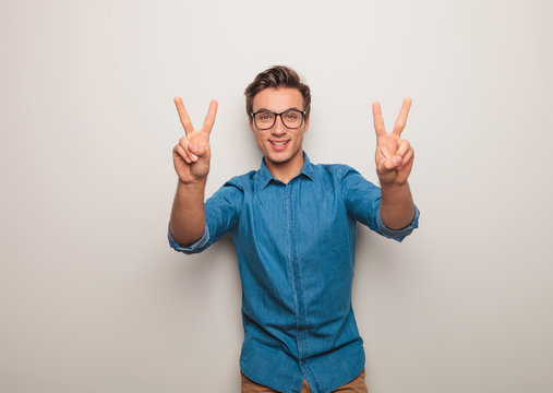 smiling young casual man making victory sign
