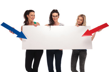 happy casual women pointing arrows to a big blank board