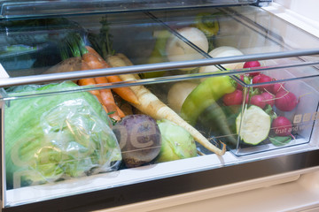 Open fridge , drawer filled with fresh vegetables