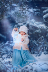 Winter fairytale. Little girl with lightning in frozen forest on Christmas eve
