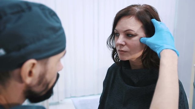 plastic surgeon checking middle aged woman face before cosmetic surgery