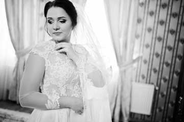 Fototapeta premium Young brunette bride posed on her room at wedding day. Black and
