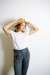 Girl holding hands on a straw hat, looking sideways