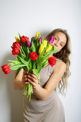 Girl with a large bouquet of colorful spring tulips