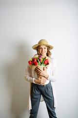 Young woman in a hat standing with a a bouquet of flowers in han