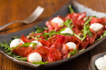 Beef carpaccio served with balls of mozzarella cheese, arugula a