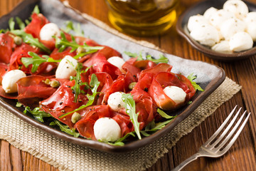 Beef carpaccio served with balls of mozzarella cheese, arugula a