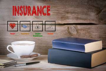 Insurance. Stack of books on wooden desk.