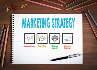 Marketing Strategy. Notebooks, pen and colored pencils on a wooden table.
