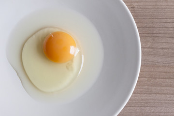 Eggs cooking for breakfast, a protein form yolk and albumen on a white background, or on a plain wooden table.