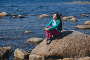 Tourist girl sitting on a rock against the sea