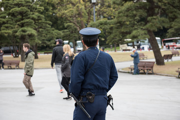 A japanese cop watching at the people can be seen in the picture. Few people and big trees can be...