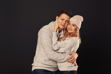 Cheerful couple in winter clothes hugging and kissing. Low light