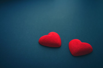 Two bright red hearts on dark blue background, St Valentines Day concept
