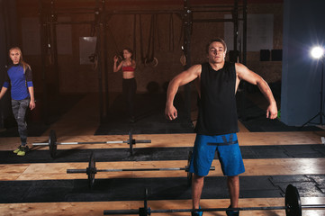 Group of sporty adults doing barbell workout