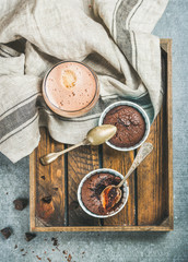 Chocolate souffle in individual baking cups and chocolate mocha coffee in wooden serving tray over...