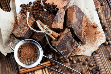 dark chocolate pieces on paper on wooden table with coffee bean,