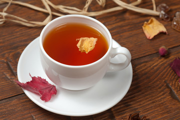 Cup of tea on wooden table with rose petals