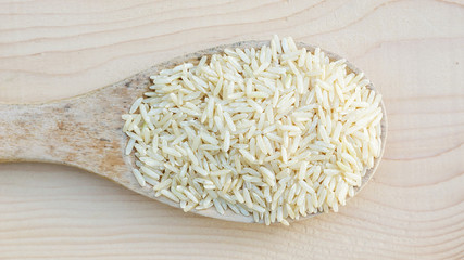 brown rice in a wooden spoon.