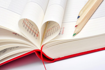 Date in red notebook, heart of pages and color pencils.