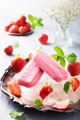 Homemade strawberry popsicles on metal plate with ice and berries. Summer food concept.