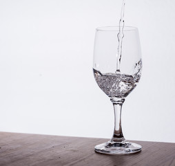 Wasserglas, halbvoll vor hellem Hintergrund