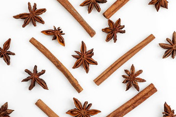 Composition made of star anise and cinnamon sticks isolated on white. Abstract pattern flat lay, top view.
