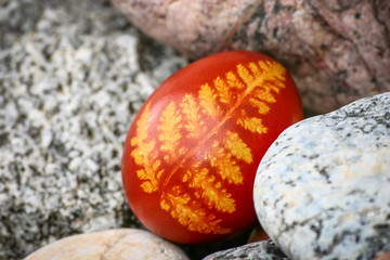 Beautiful red colored Easter egg between pebbles