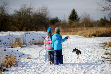 Fototapeta na wymiar Two children and their dog on winter walk.