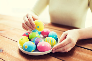close up of woman hands with colored easter eggs