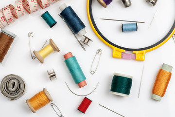 Spools of thread, needles and other sewing stuff on a white background, flat lay composition, close-up